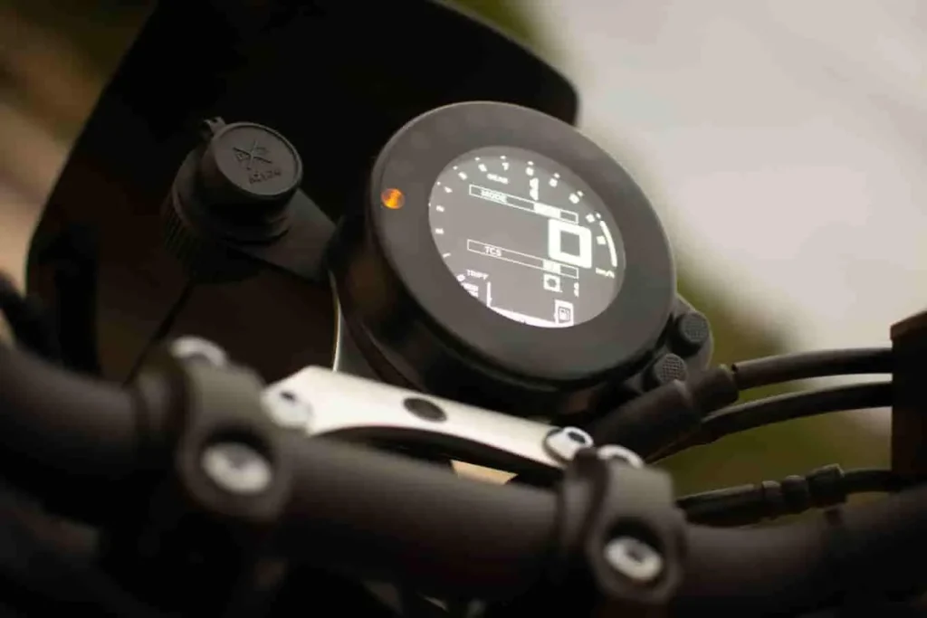 Tableau de bord Yamaha TZR 50, écran digital rond avec données de conduite et voyant orange allumé.