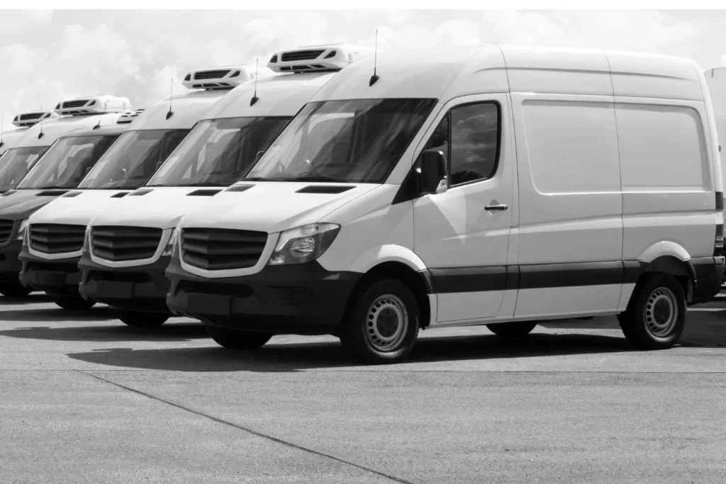 T5 utilitaires blancs avec groupe froid, garés en série sur un parking logistique.