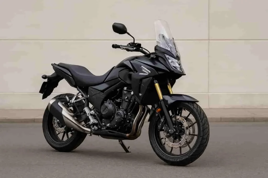 Honda CB500X noire garée sur asphalte devant mur béton clair.