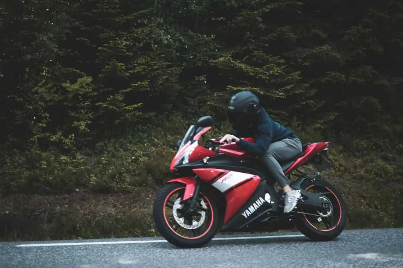 Yamaha TZR 50 Yamaha TZR 50 rouge en pleine route, pilote penché vers l’avant, posture sportive et allure dynamique.