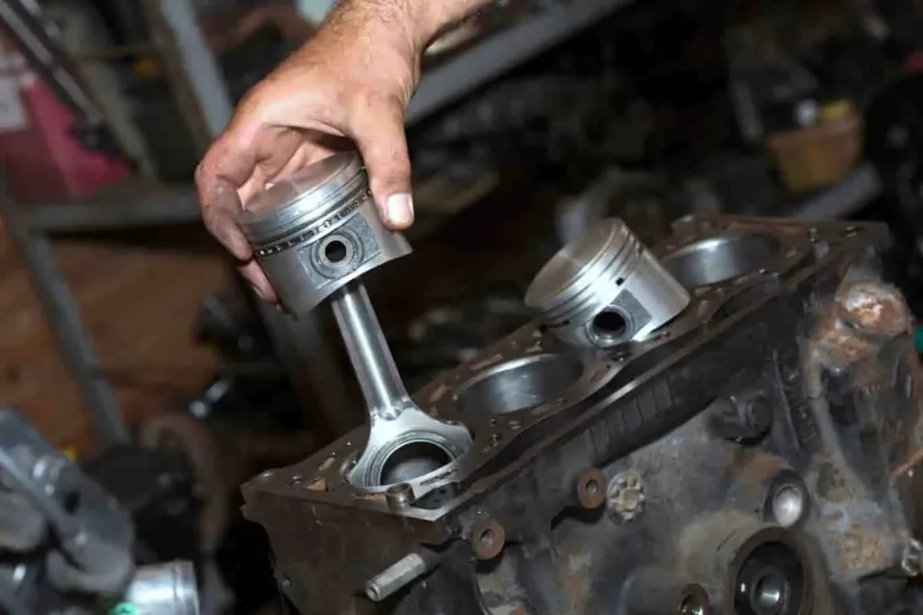 Montage moteur : insertion du piston et de la bielle, zone du coussinet visible, pièce clé pour réduire les frottements sur le vilebrequin.