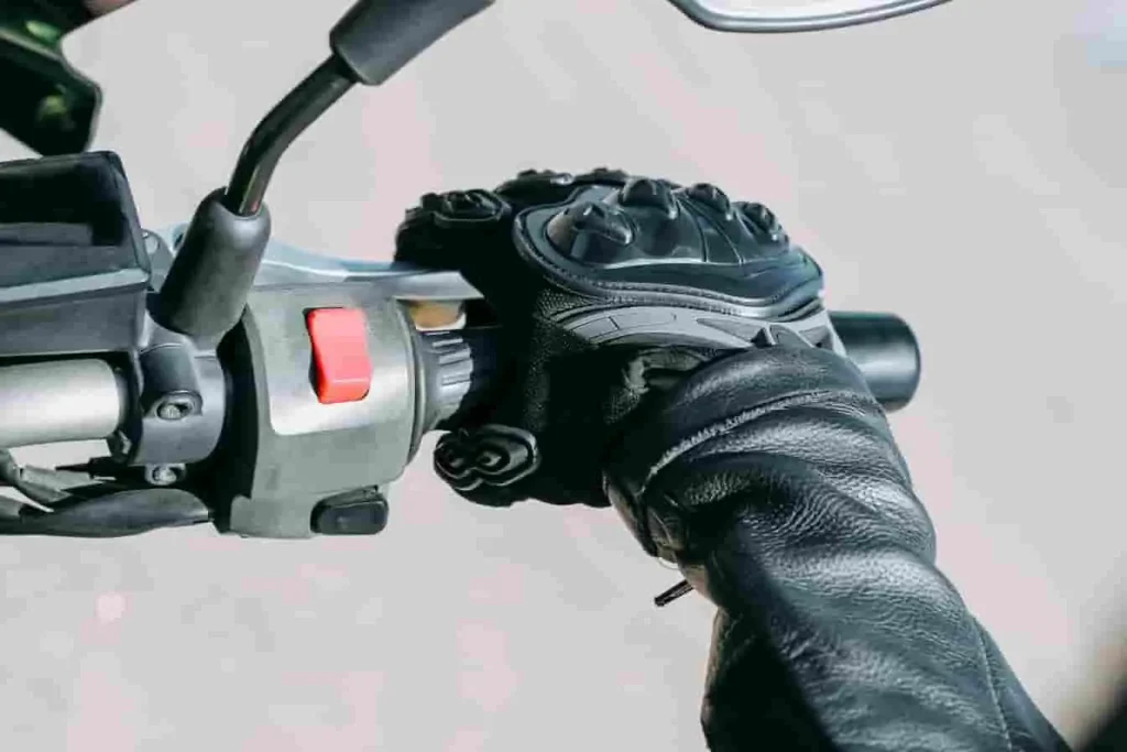 Poignée de moto tenue fermement par une main gantée, image évoquant la maîtrise et la concentration du pilote.
