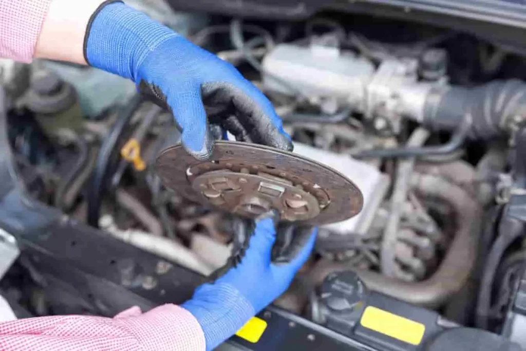 Disque d’embrayage inspecté au-dessus du moteur, étape clé dans le processus de changement d’embrayage sur véhicule manuel
