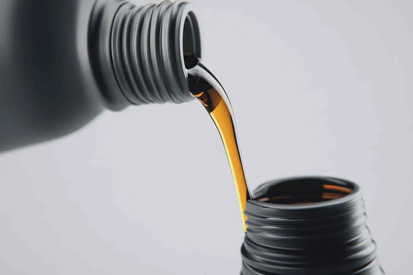 huile pour direction assistée Liquide doré transféré entre deux contenants noirs, huile utilisée pour entretenir la direction assistée du véhicule.