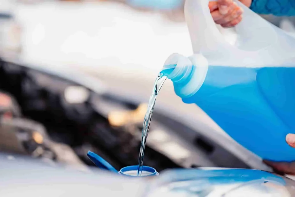 Liquide bleu versé dans le réservoir moteur, étape de vidange du liquide de refroidissement pour garantir une température stable