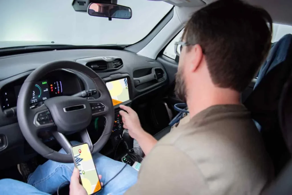 Conducteur vérifiant son itinéraire sur smartphone et écran de bord, image liée à un bug de synchronisation Waze.