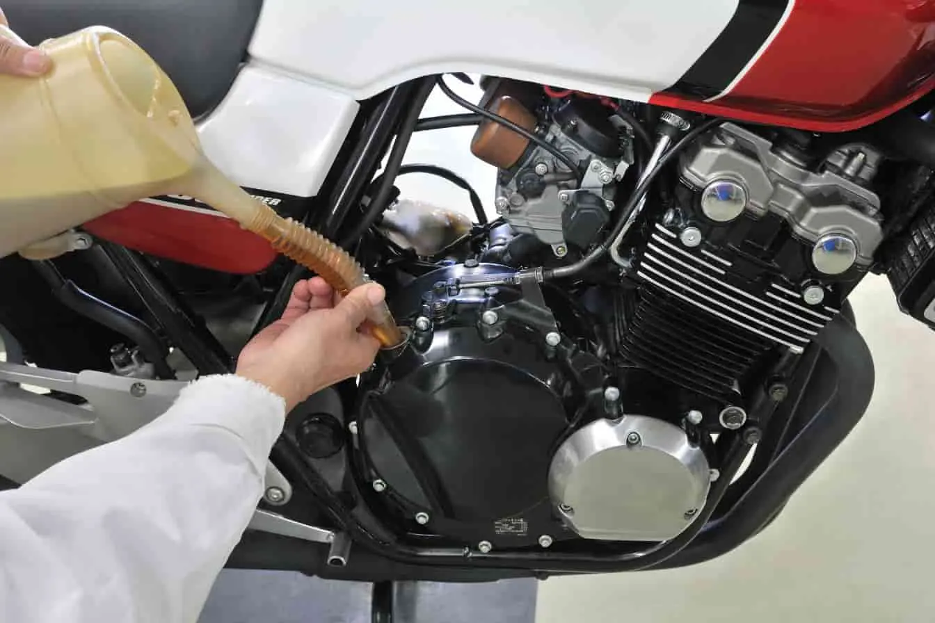 vidange moto Vidange moto en cours : huile moteur versée via entonnoir souple dans le réservoir, opération essentielle pour l’entretien.