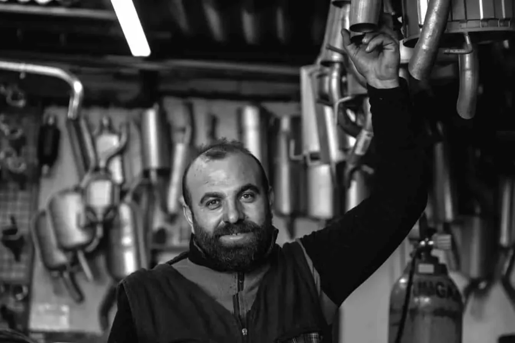 Mécanicien dans un garage rempli de pots d’échappement, ambiance typique d’un lieu où l’on répare les échappements fissurés