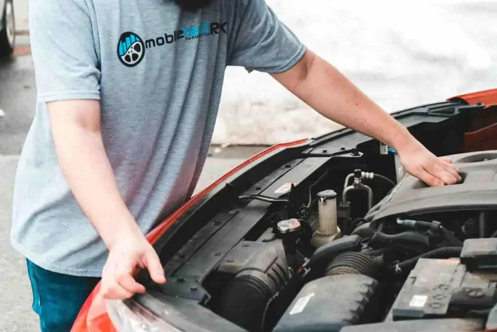 Moteur TCe exposé sous capot ouvert, avec intervention technique d’un mécanicien en t-shirt gris dans un garage
