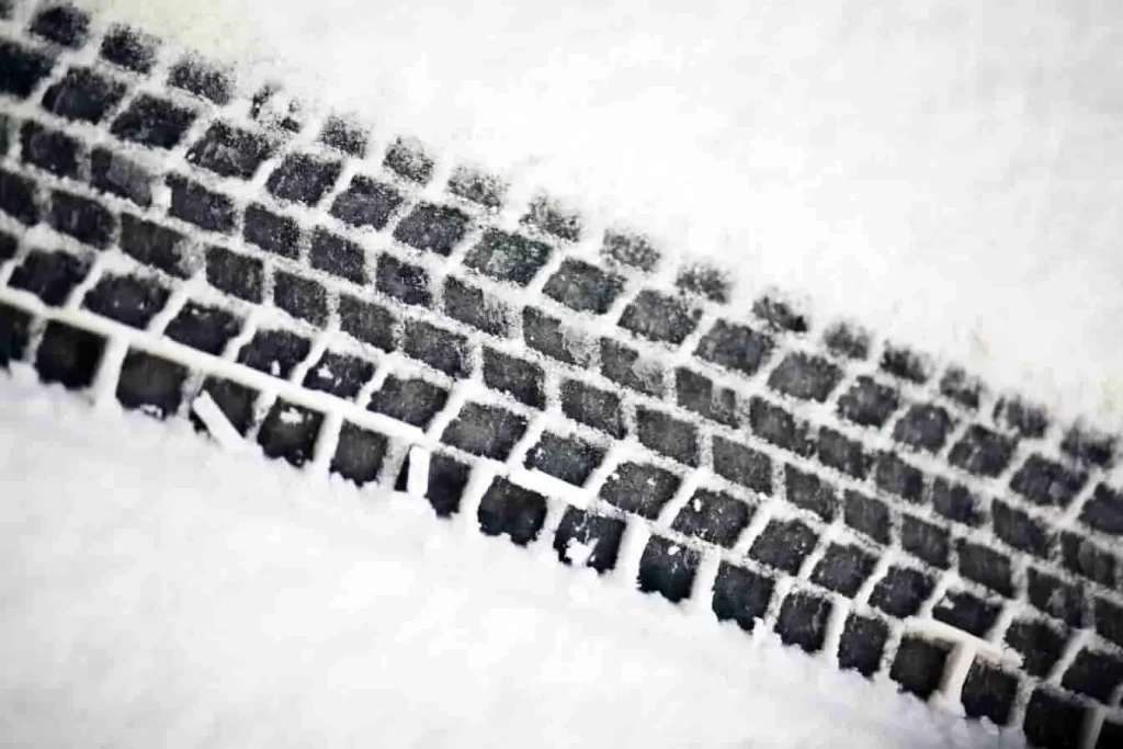 Trace nette de pneu dans la neige fraîche, sculpture bien dessinée, image d’une adhérence hivernale assurée sur route froide