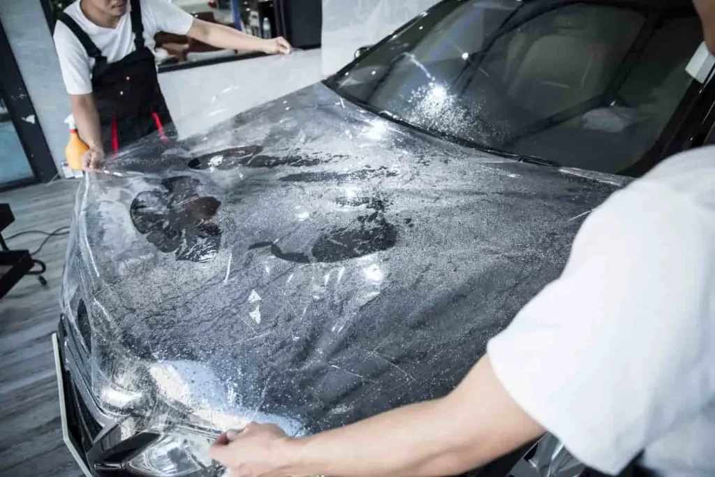Film transparent appliqué sur le capot d’une voiture, étape préparatoire avant peinture pour protéger les zones sensibles