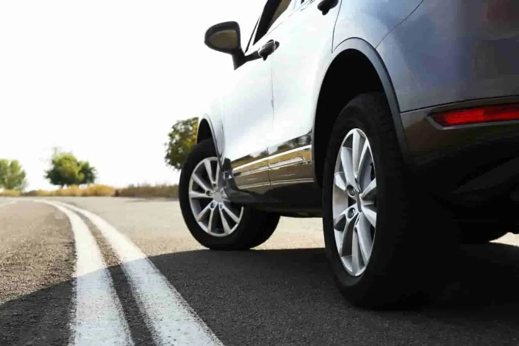 SUV roulant sur route sinueuse avec ciel dégagé, image qui illustre une voiture hybride non rechargeable en pleine conduite