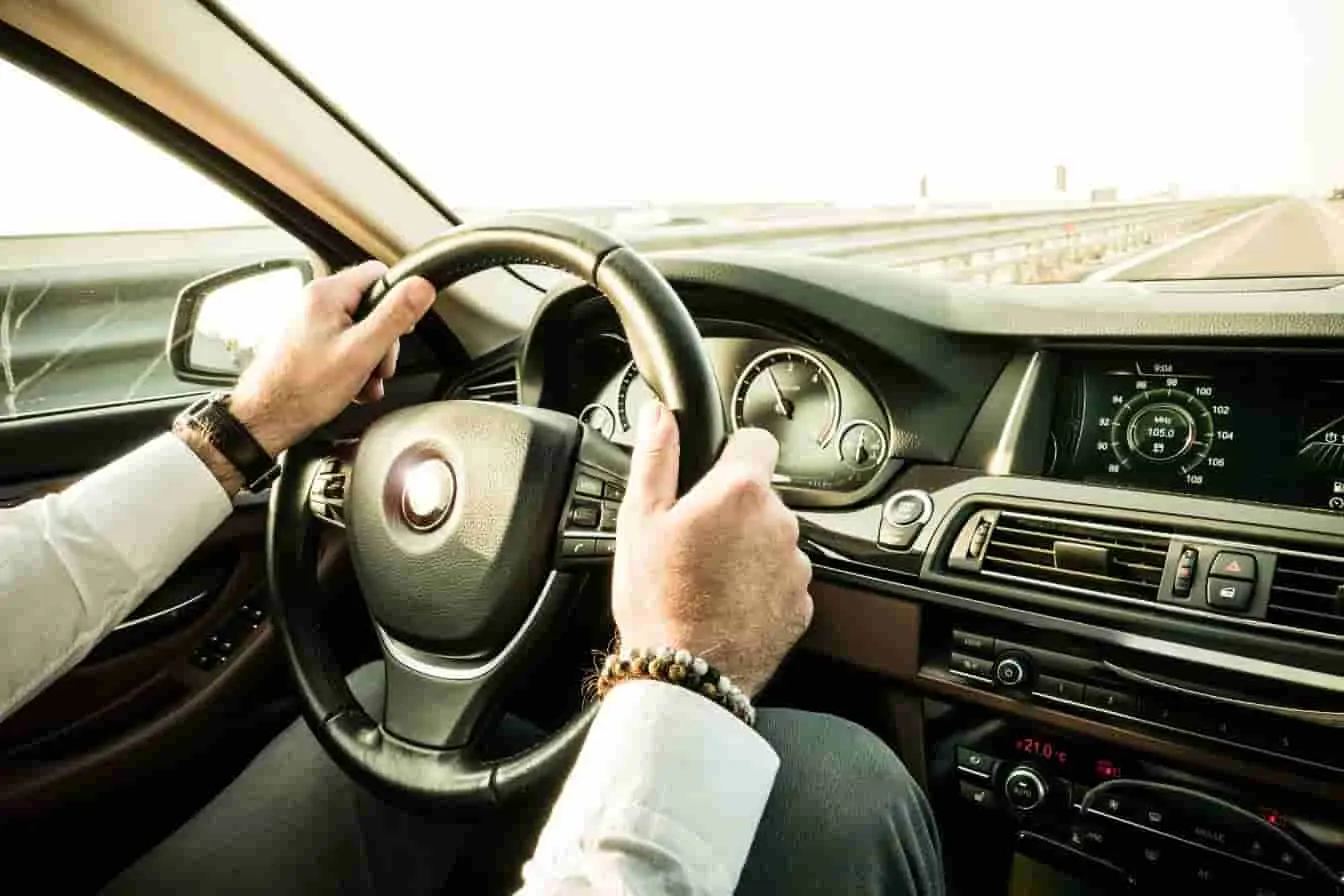 Vibrations du volant Mains sur le volant, route dégagée, image évoquant les sensations de vibration ressenties en conduite