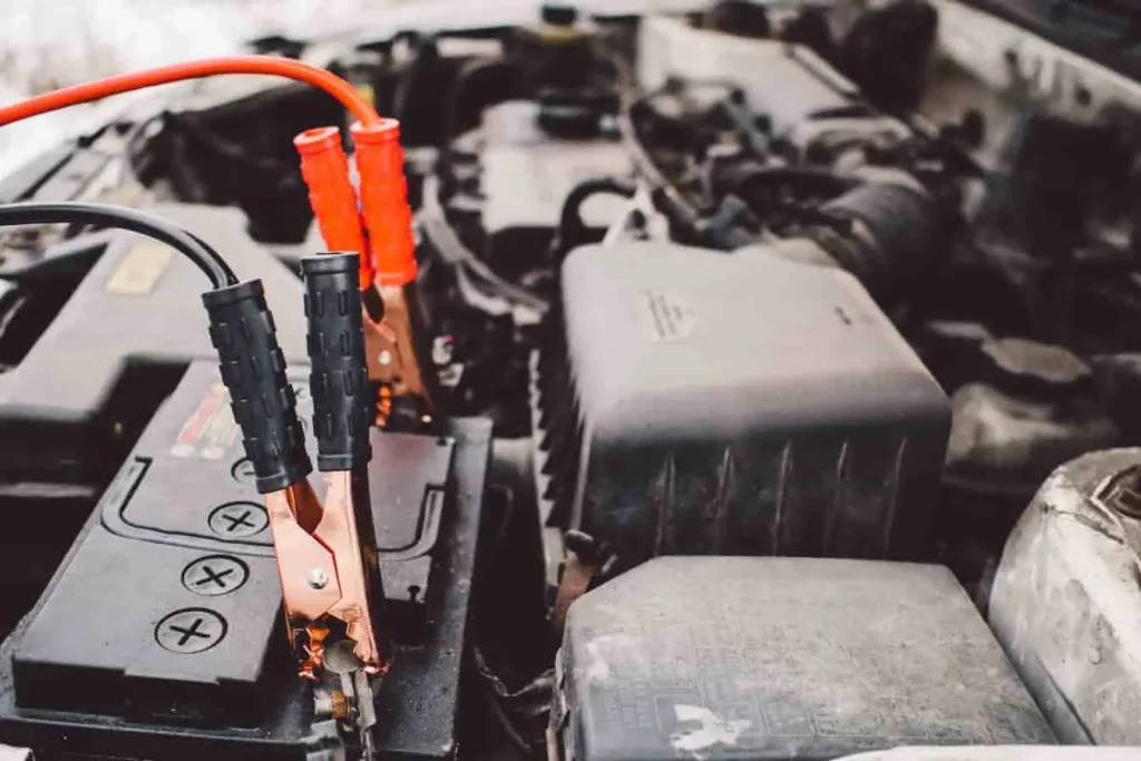 Batterie de voiture avec câbles rouge et noir, image qui reflète le rôle du BMS dans la surveillance des tensions et des charges