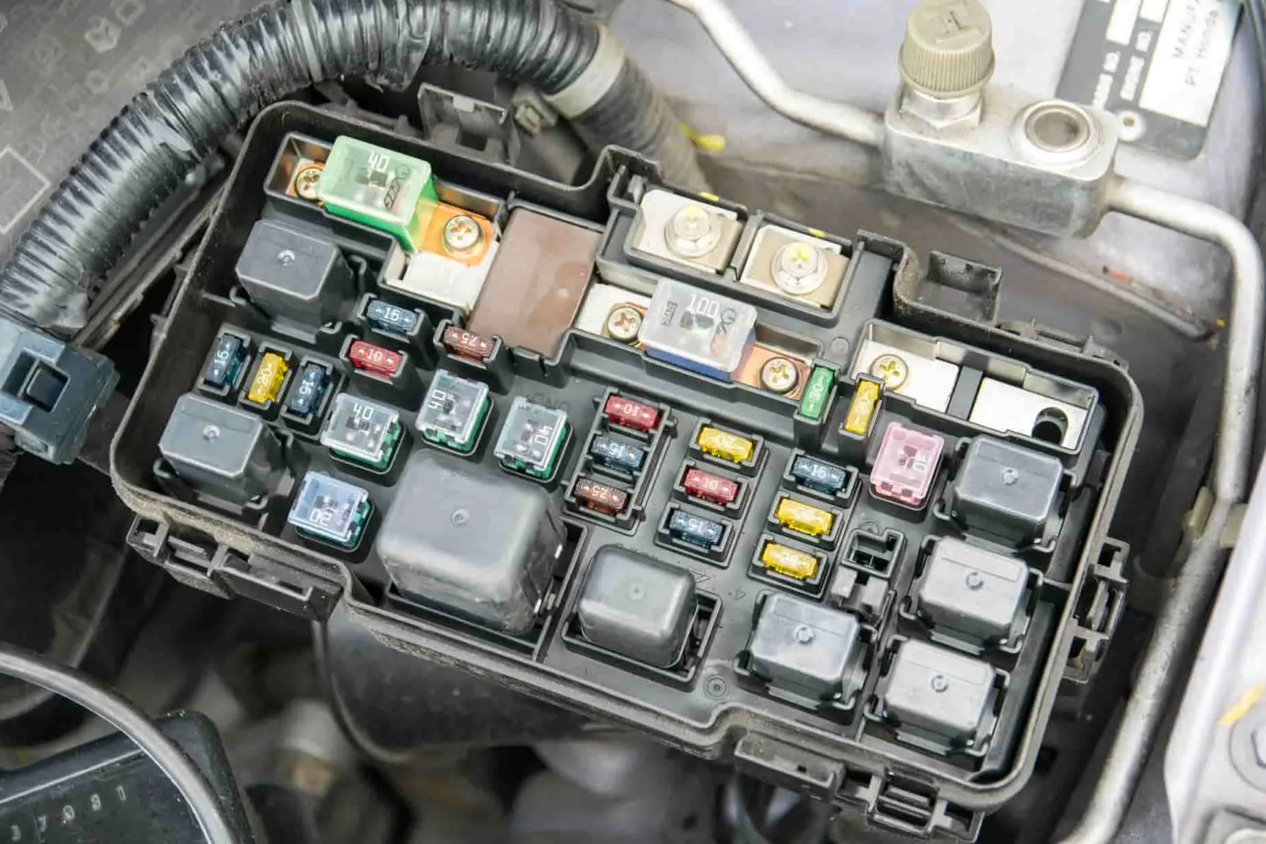 boîtier de servitude intelligent dans l’automobile Vue rapprochée d’un boîtier électrique automobile ouvert, fusibles colorés et relais visibles, image illustrant le rôle du BSI dans la gestion des fonctions