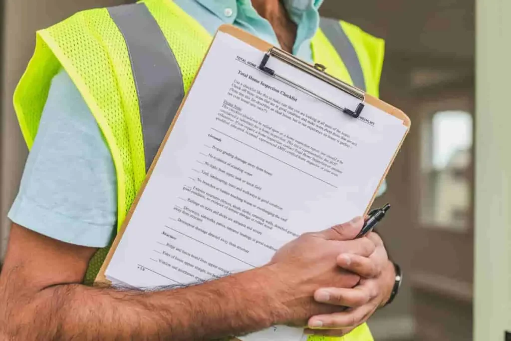 Homme en gilet de sécurité avec clipboard, checklist en main, image d’une contre-visite voiture pour confirmer la conformité post-intervention