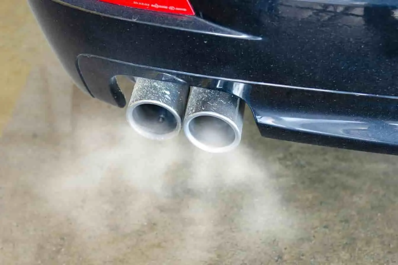 échappement voiture fissuré Deux sorties d’échappement métalliques avec fumée visible, image évoquant un échappement possiblement fissuré sur une voiture en marche