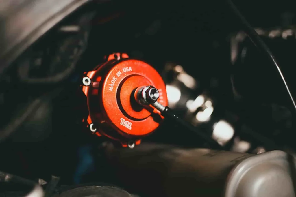 Vue rapprochée d’un composant rouge TIAL connecté à une durite, élément clé du système turbo pouvant générer un sifflement normal ou révélateur d’un souci