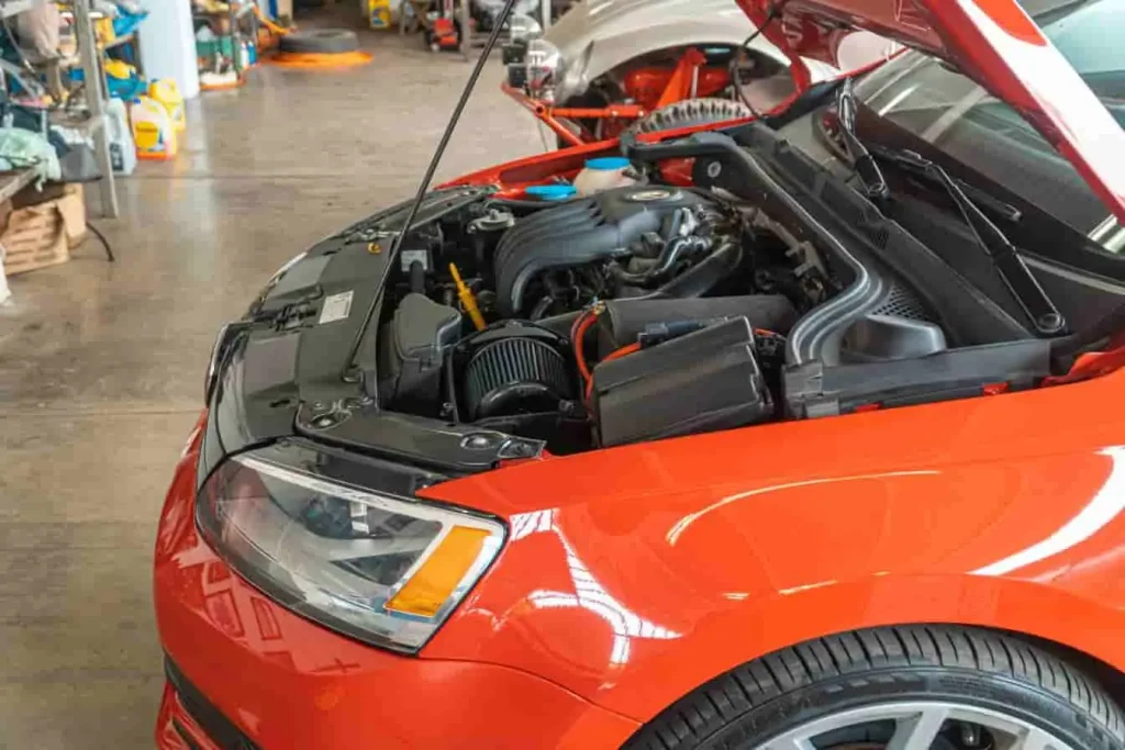 Voiture rouge capot ouvert en atelier, image qui évoque une inspection moteur liée au code défaut P0420 indiquant une efficacité catalyseur insuffisante.