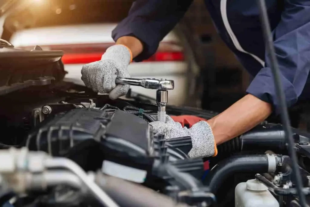 Mécanicien en gants serrant un boulon moteur, image qui évoque une intervention liée au code défaut P0420 indiquant un catalyseur inefficace.