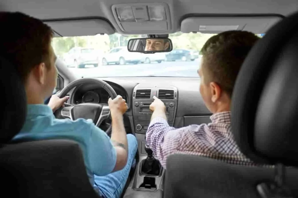 Moniteur auto-école assis à côté d’un élève au volant, image illustrant une session de formation pratique en situation réelle