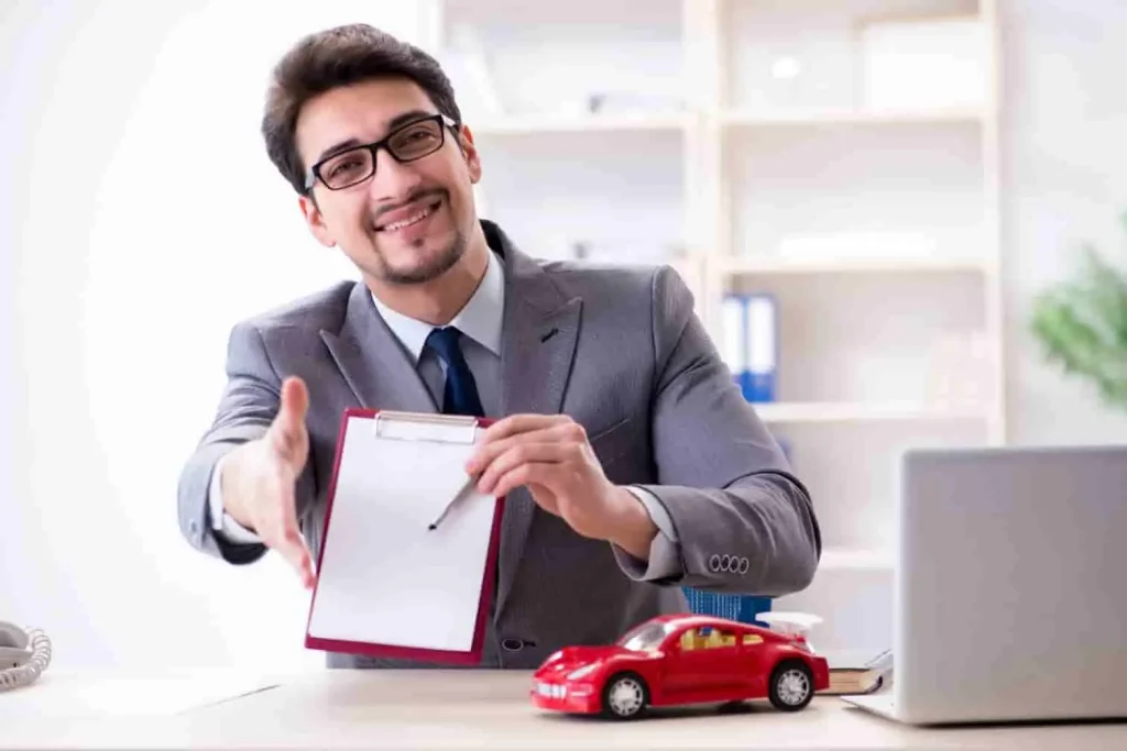 Homme en costume tendant la main avec un stylo et un contrat vierge, image illustrant une démarche de résiliation d’assurance auto en face à face.