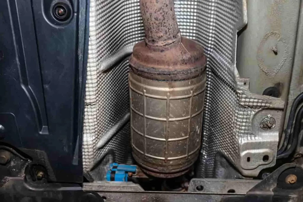Filtre à particules cylindrique installé dans le système d’échappement, entouré de blindage thermique et fixé sous le châssis du véhicule.