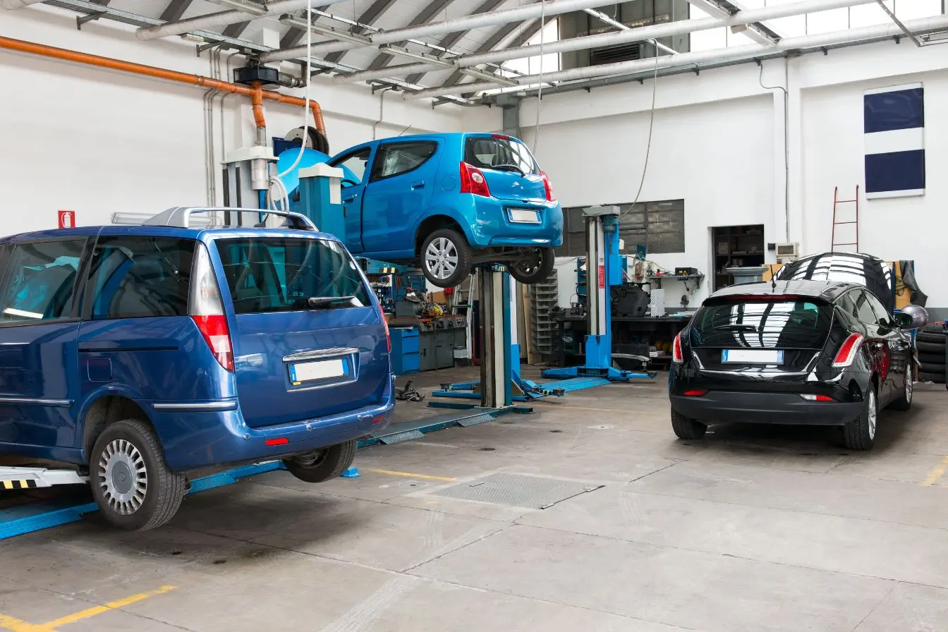 Petite voiture bleue sur pont élévateur au centre d’un atelier, image qui reflète un garage équipé pour réparations en autonomie
