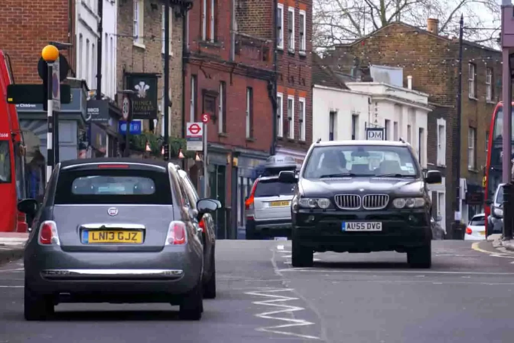 Scène urbaine avec Fiat et BMW sur route britannique, image d’un parc automobile à moderniser