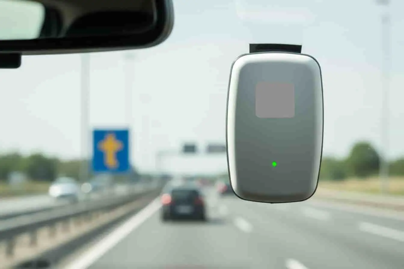 badge télépéage Vue depuis l’habitacle avec badge télépéage actif sur pare-brise, autoroute en arrière-plan