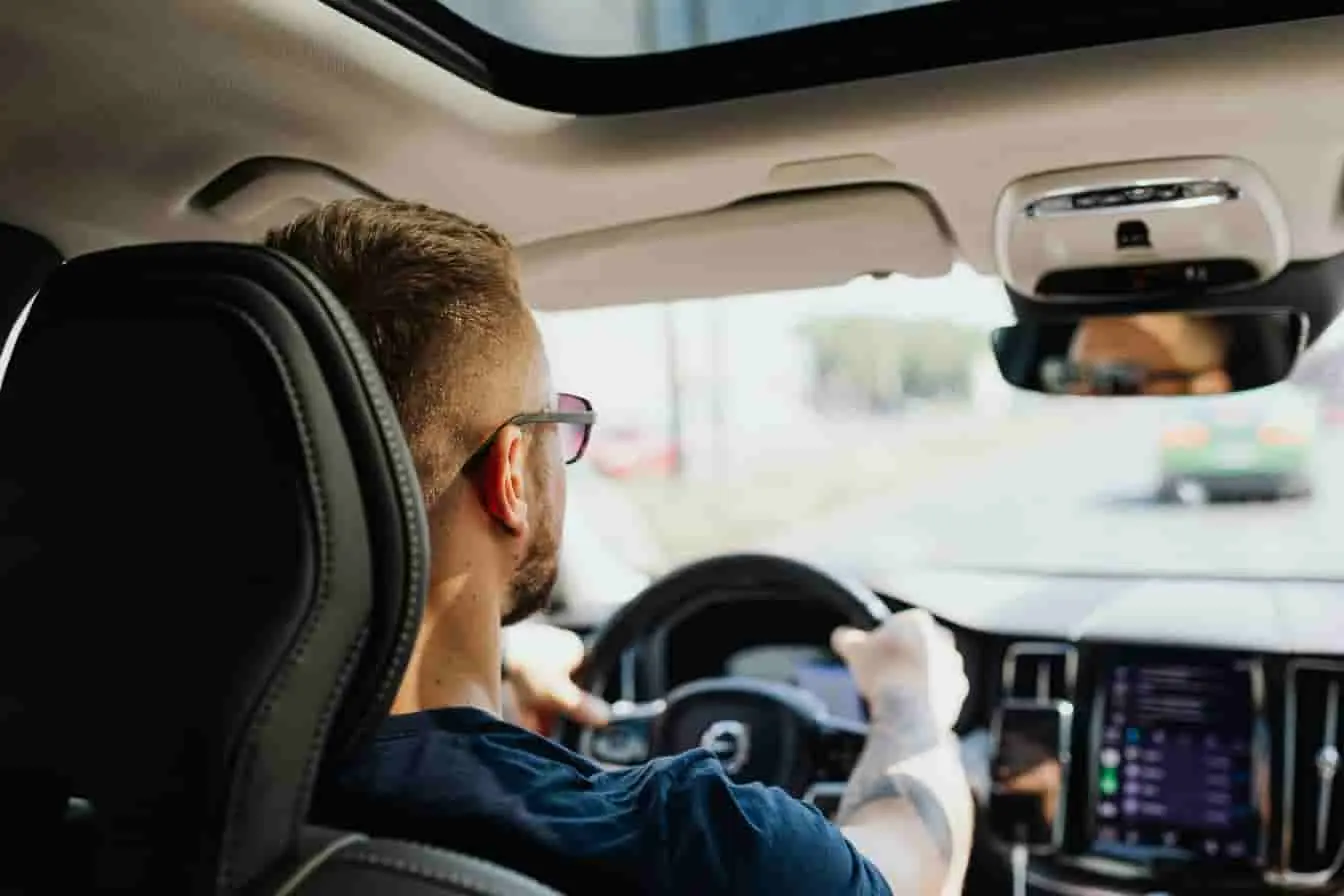 commande vocale en voiture Vue arrière d’un conducteur dans un habitacle lumineux avec écran digital, image qui reflète une situation liée à un dysfonctionnement vocal embarqué