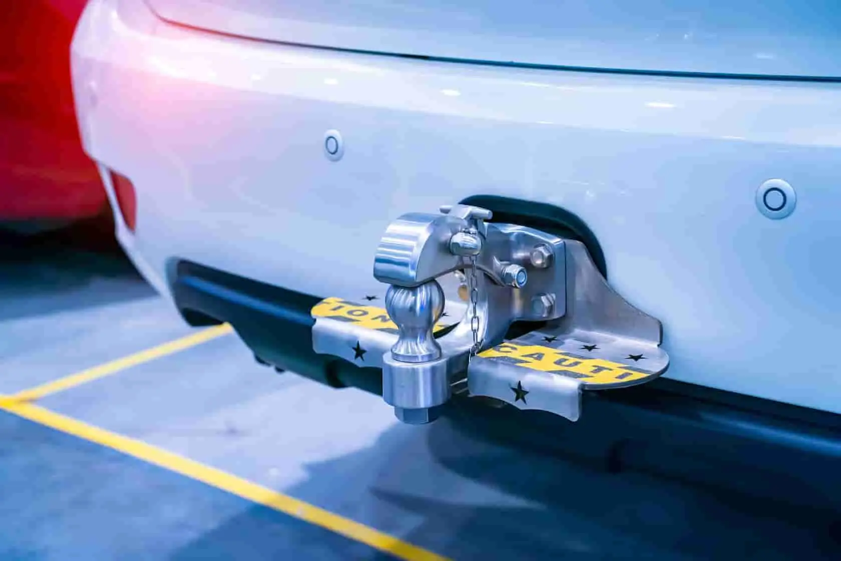 installer un attelage Attelage robuste fixé sous le pare-chocs d’un véhicule avec boule brillante et marquage de précaution