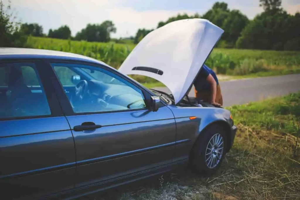 Personne inspectant le moteur d’une voiture en panne sur route rurale, scène typique d’un souci lié au colmatage du FAP