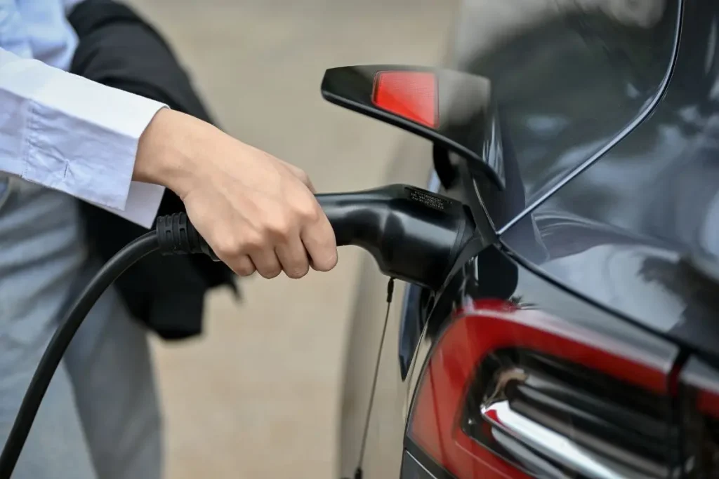 Main branchant un câble de recharge à l’arrière d’un SUV moderne, image d’un Tesla en cours de chargement