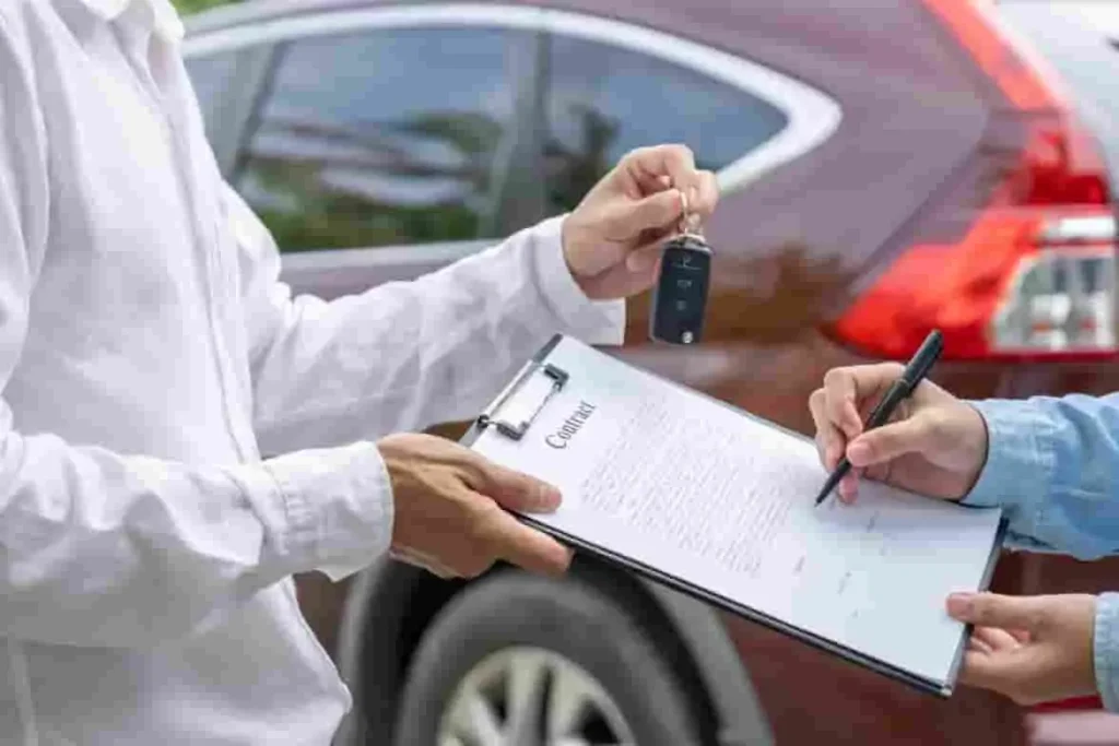 Une personne signe un contrat sur une tablette pendant qu’une clé est tendue, illustrant la vente d’un véhicule