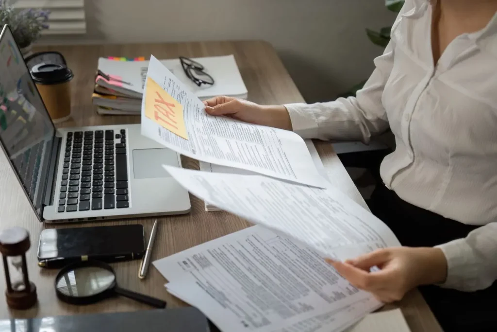 Personne en costume examinant des documents fiscaux sur bureau, image d’une constitution de dossier pour la DREAL