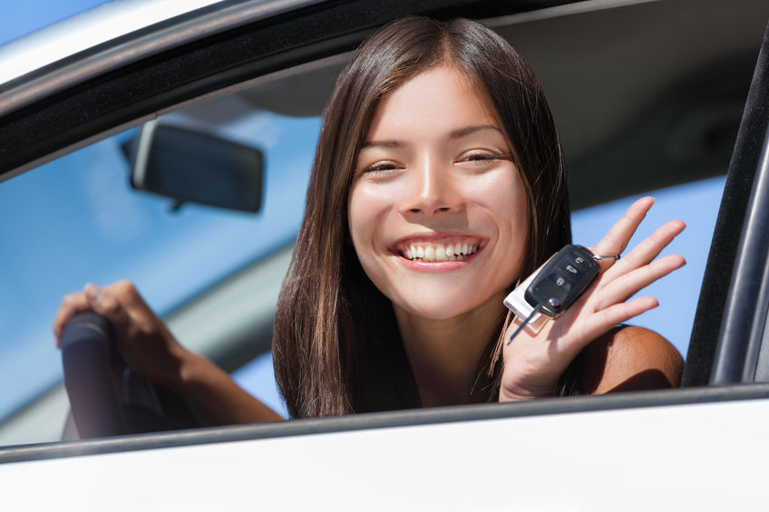 Happy Asian girl teen driver showing new car keys