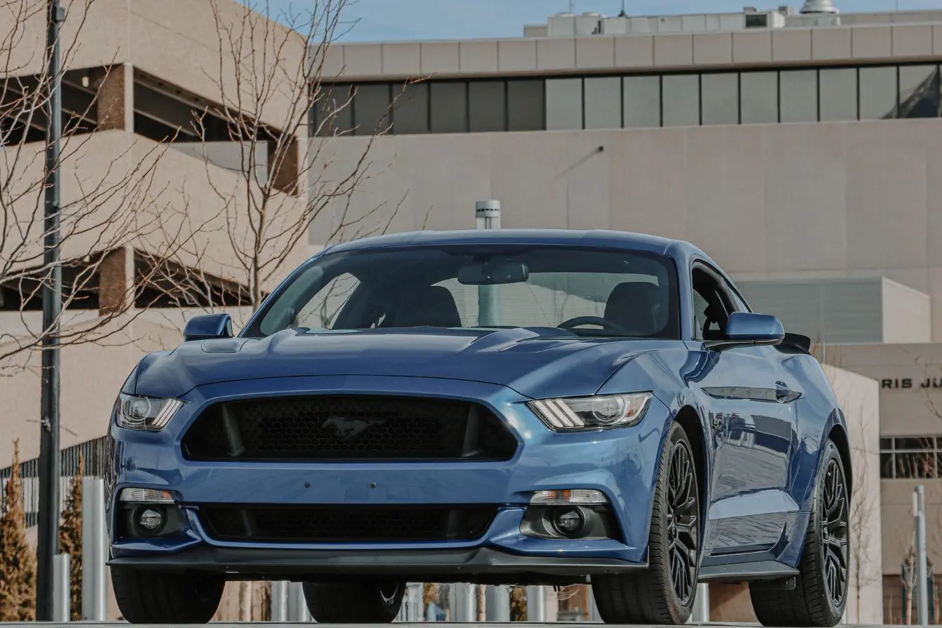 Ford Mustang Mach-E Ford Mustang Mach-E bleu garée devant un bâtiment moderne, image d’un SUV électrique au style affirmé