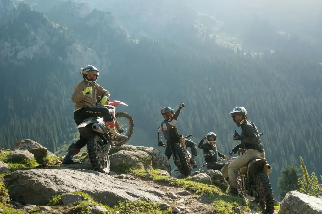 Quatre motards en tenue complète posés sur terrain rocailleux, motos trail prêtes pour l’aventure A2