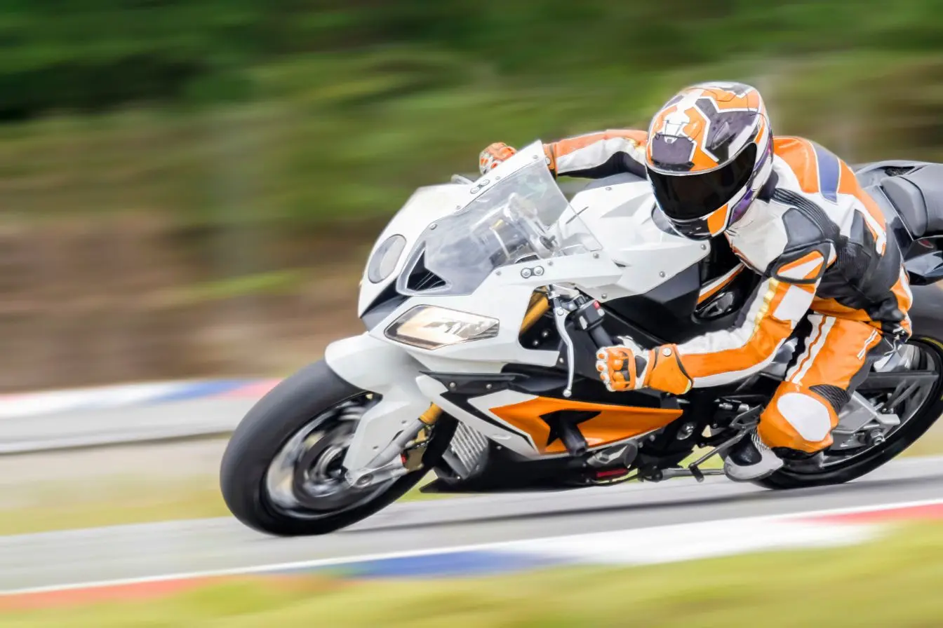 Pilote en pleine courbe sur moto blanche et orange, image d’une posture typique de Francesco Bagnaia