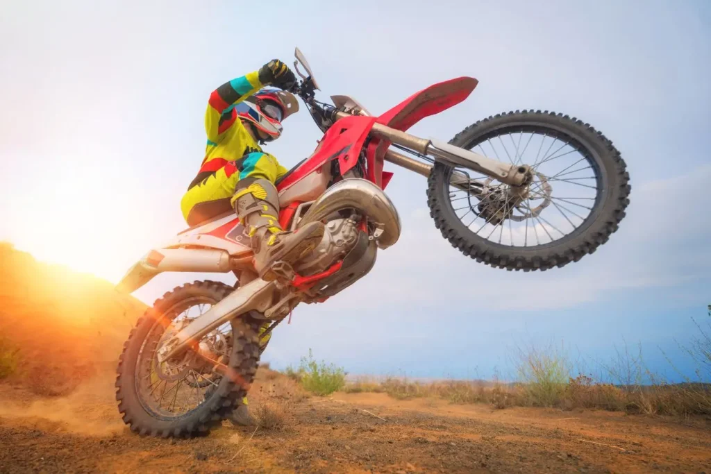 Motard en tenue colorée réalisant un wheeling sur piste sèche, image évoquant la puissance du Yamaha DTR 125