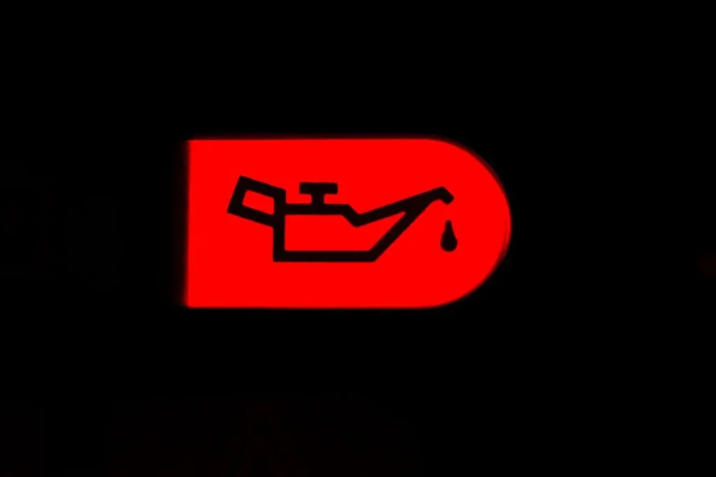 Icône rouge en forme de bidon d’huile avec goutte affichée sur fond noir, image évoquant une alerte moteur urgente