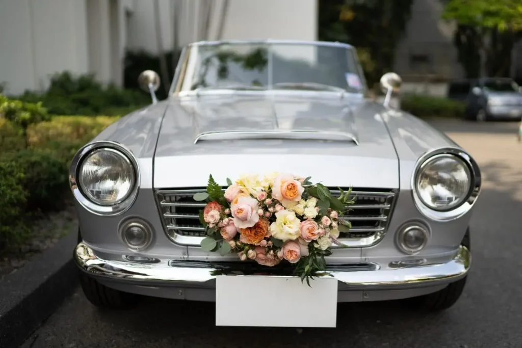 Bouquet floral fixé sur calandre de voiture vintage argentée, visuel élégant suggérant un coût de location nuptiale personnalisé