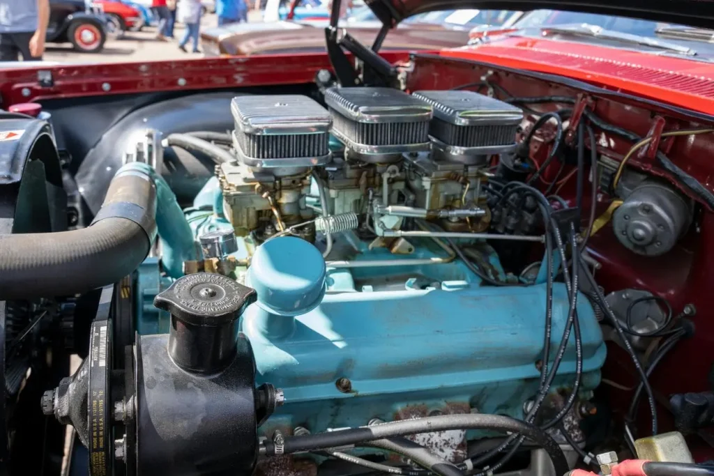 Bloc moteur bleu ciel dans une baie moteur rouge, montrant les collecteurs et les filtres à air chromés