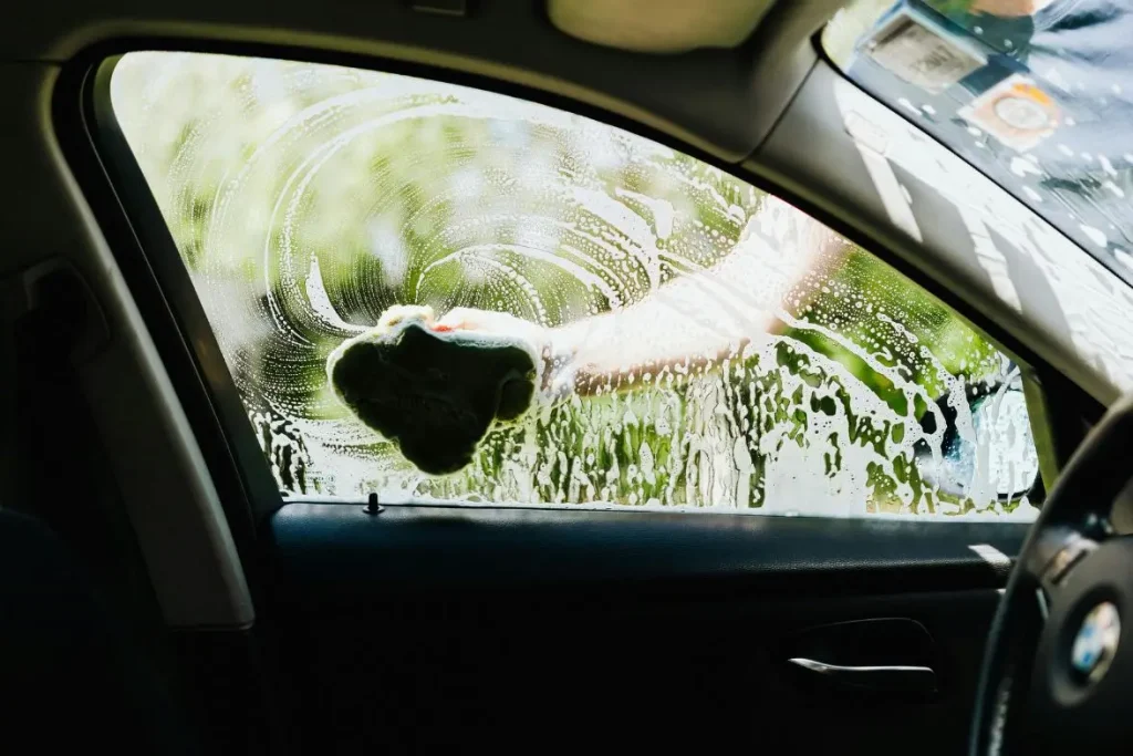 Nettoyage d'une vitre auto avec de la mousse blanche épaisse