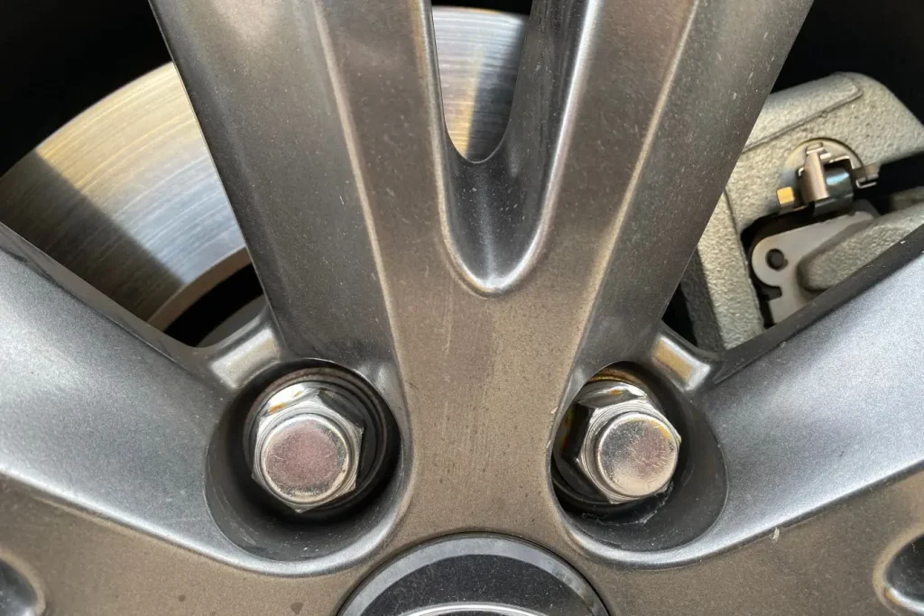 Gros plan sur jante métallique avec écrous et disque de frein, image illustrant le système de roulement dans une voiture