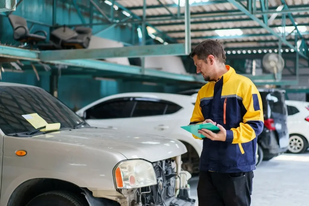 Voiture abîmée dans atelier avec technicien prenant des notes, image évoquant le contrôle du numéro VIN