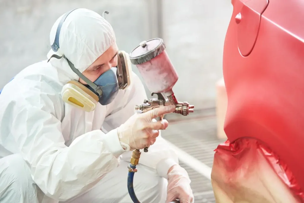 Peintre en combinaison appliquant une couche, image d’un traitement contre rayure profonde sur carrosserie