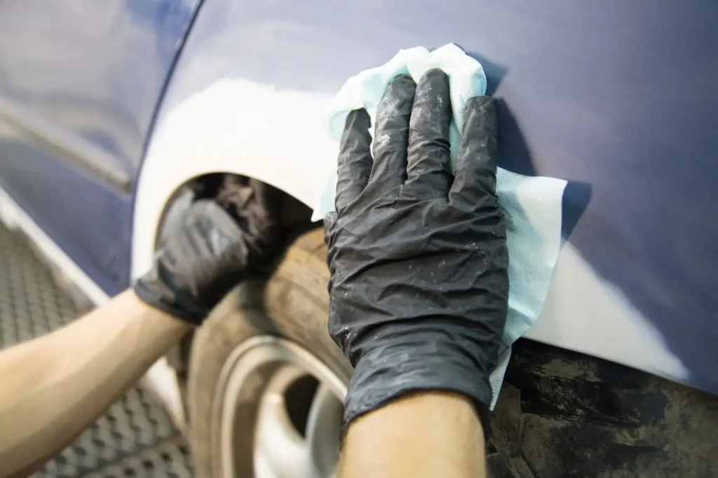 Nettoyage méticuleux d'un véhicule bleu avec un chiffon spécial pour éliminer la résine sur la carrosserie