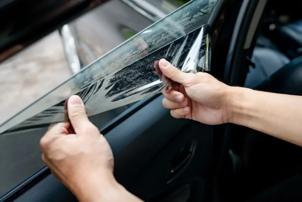 Film teinté partiellement décollé sur vitre de voiture représentant le respect des normes de transparence imposées